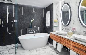 a bathroom with two sinks and a tub and mirrors at Mandarin Oriental, Munich in Munich