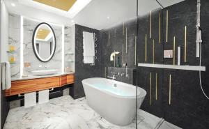 a bathroom with a tub and a sink and a mirror at Mandarin Oriental, Munich in Munich