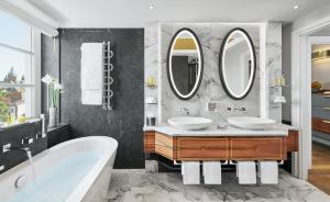 a bathroom with two sinks and two mirrors at Mandarin Oriental, Munich in Munich