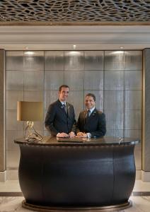 two men in suits sitting at a desk at Mandarin Oriental, Munich in Munich