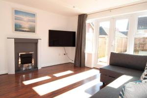 a living room with a television and a fireplace at The Voyager - Newly Furnished Home in Derby