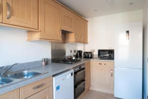 a kitchen with wooden cabinets and a white refrigerator at The Voyager - Newly Furnished Home in Derby