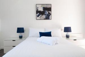 a white bedroom with a large white bed with two lamps at The Voyager - Newly Furnished Home in Derby +21 photos