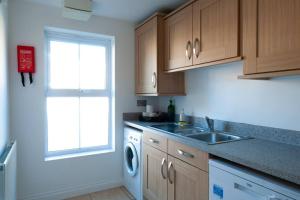 a kitchen with a sink and a washing machine at The Voyager - Newly Furnished Home in Derby