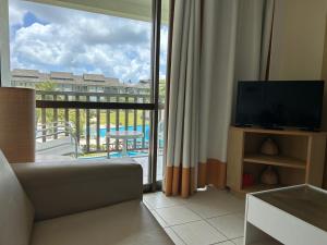 a living room with a television and a view of a balcony at Beach Class Porto de Galinhas in Porto De Galinhas