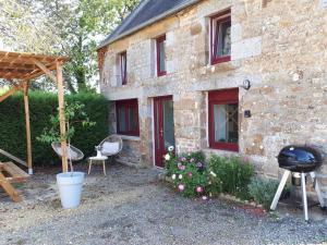 a stone house with a grill and chairs in front of it at Le Gite de la Menuiserie in Maisoncelles-la-Jourdan
