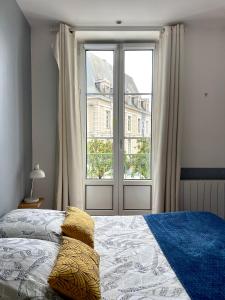 una camera da letto con un letto e una grande finestra di Le balcon de la place a Dinan
