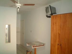 Habitación con ventilador de techo y TV en la pared. en Residencial Paraiso, en Florianópolis