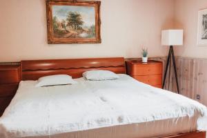 een slaapkamer met een wit bed met een schilderij aan de muur bij Veskivee Külalistemaja in Umbusi