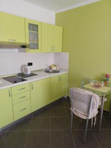 a kitchen with green cabinets and a table and a chair at Apartman Pometo II in Poreč