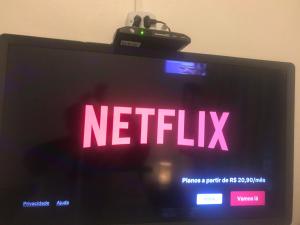 a television with the words netflix on the screen at Chalés e Flats Refúgio de Camburi in Camburi +57 photos