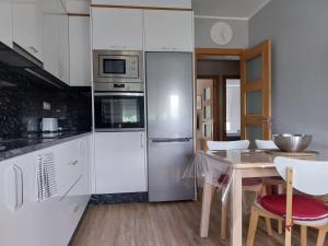 a kitchen with white appliances and a table with chairs at Apartamento Salgueiro ORTIGUEIRA in Santa Marta de Ortigueira