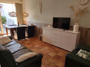 a living room with a couch and a flat screen tv at ASTERIAS Bed by the Sea in Westkapelle
