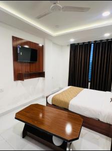 1 dormitorio con 2 camas, mesa y TV en Hotel Shiv, en Indore