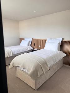 two beds in a room with white sheets and pillows at Relax & unwind in Fraserburgh