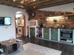 een keuken met groene kasten en een stenen muur bij DE ZEEBRIES Bed by the Sea in Westkapelle