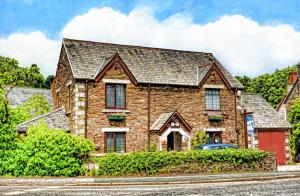 ein großes Backsteinhaus mit einem Auto davor in der Unterkunft Kingfisher Cottage in Tavistock