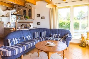 a living room with a blue couch and a table at Ginster in Zingst +9 photos