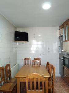 a kitchen with a wooden table with chairs and a television at A casiña de Tuli in Vigo