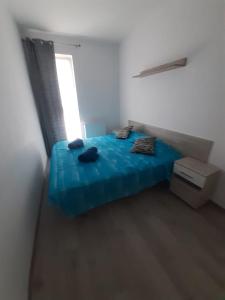 a blue bed in a white room with a window at Cozy Studio in Târgu-Mureş