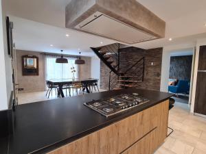 a kitchen with a black counter top and a stove at Villa Ty Mam Goz, 50m mer, piscine intérieure, SPA, 11 personnes in Santec