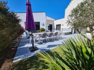 a patio with a table and chairs and an umbrella at Villa Ty Mam Goz, 50m mer, piscine intérieure, SPA, 11 personnes in Santec