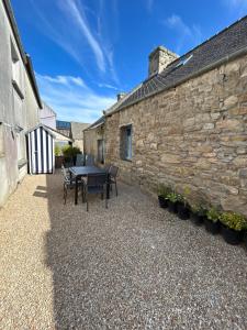 a patio with a table and chairs next to a stone building at Dans le petit bourg in Santec