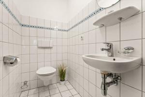 a white bathroom with a sink and a toilet at Ferienwohnung Nordlicht in Greetsiel +19 photos