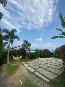a stone walkway with a palm tree and a cloudy sky at Panorama Pueblo Tapao in Armenia