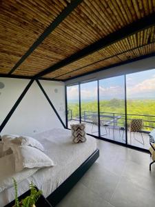 a bedroom with a bed and a balcony with windows at Panorama Pueblo Tapao in Armenia +33 photos