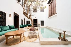 マラケシュにあるRIAD Ylha MARRAKECHのリビングルーム(プール、ソファ、テーブル付)