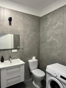 a bathroom with a toilet and a sink and a washing machine at Abra Apartment X in Poznań