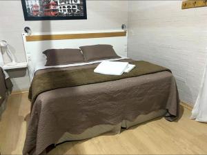 a bedroom with a large bed with two towels on it at Pousada dos Pássaros in Gramado