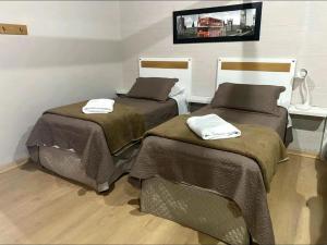 two beds with towels on them in a room at Pousada dos Pássaros in Gramado