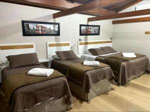 a room with three beds with brown blankets at Pousada dos Pássaros in Gramado