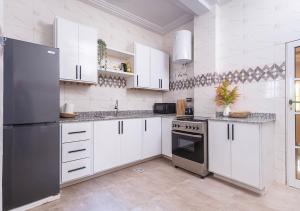 Una cocina con gabinetes blancos y un refrigerador de acero inoxidable. en magnifique appartement, de deux balcons, très spacieux, en Baguida