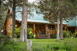 a log cabin with a porch and trees at Lonesome Duck Ranch in Chiloquin