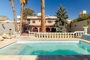 a swimming pool in front of a house with palm trees at Fliphaus Wine Country - 9 Bd 22pax Pool Jacuzzi in Godoy Cruz