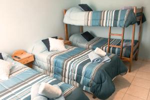 a room with three beds and a bunk bed at Rumel Quimey Quipan in Puerto Madryn
