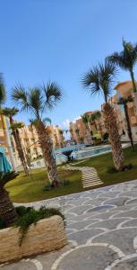 a group of palm trees in a park with buildings at Les dunes in Sousse