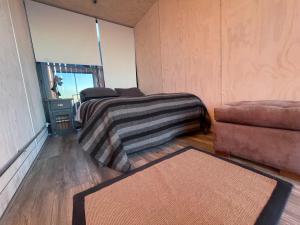 ein Schlafzimmer mit einem Bett, einer Couch und einem Teppich in der Unterkunft AKA Tiny House in Matanzas
