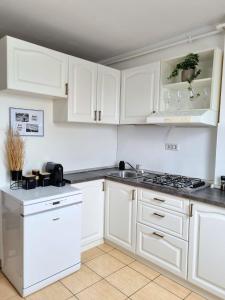 a white kitchen with white cabinets and a stove at Iulius Town Charm Cozy Apartments in Timişoara
