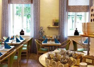 un ristorante con tavoli, sedie e finestre di Melarose Feng Shui Hotel a Berlino