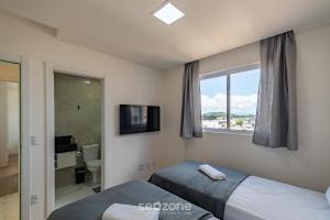 a bedroom with two beds and a tv and a window at CII - Apartamentos a 900m da Praia em Porto Belo in Perequê