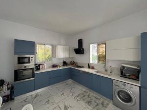 a kitchen with blue cabinets and a washer at Villa Djerba Arkou in Djerba
