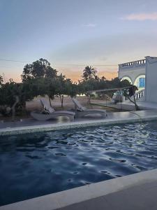 a swimming pool with chairs in the water at Villa Djerba Arkou in Djerba