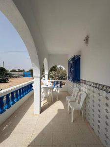 a balcony with white chairs and a view of the ocean at Villa Djerba Arkou in Djerba