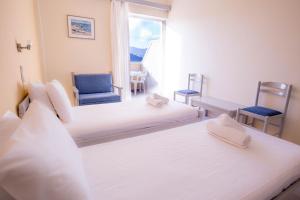 a bedroom with two beds and two chairs and a window at Galini Beach Hotel in Kissamos