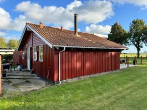 a small red building with a grassy yard at Langø Feriecenter - Panorama Sea View in Nakskov