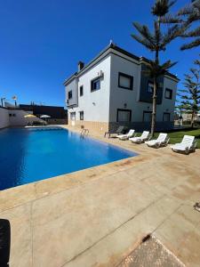 a villa with a swimming pool in front of a house at Villa Safaa Dar Bouazza in Dar Mouddene